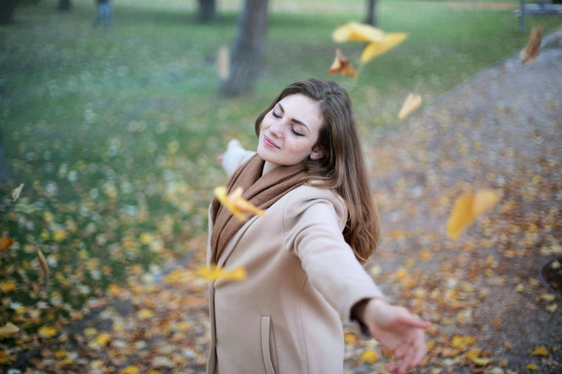 image of woman with arms raised in freedom with autumn leaves fallin gdown on them