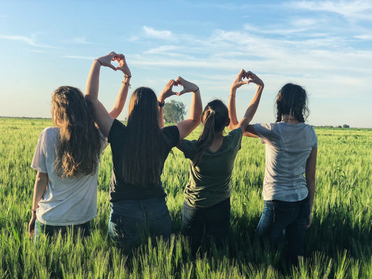 Image of women sitting making hearts with hands for Sisterhood