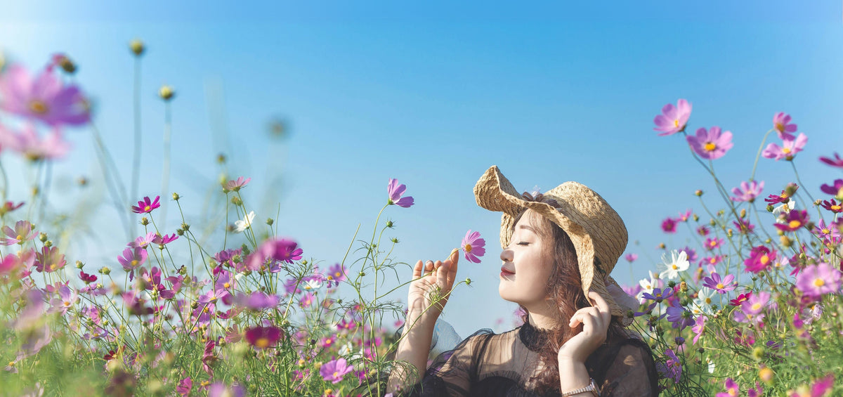 image of woman smelling purple flowers with a peaceful smile from a positive mindset