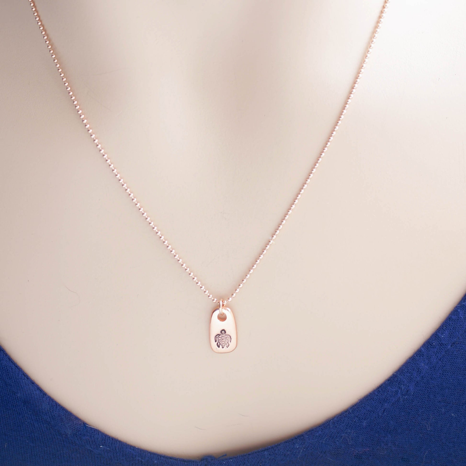 Rose gold necklace stamped with a turtle on neck