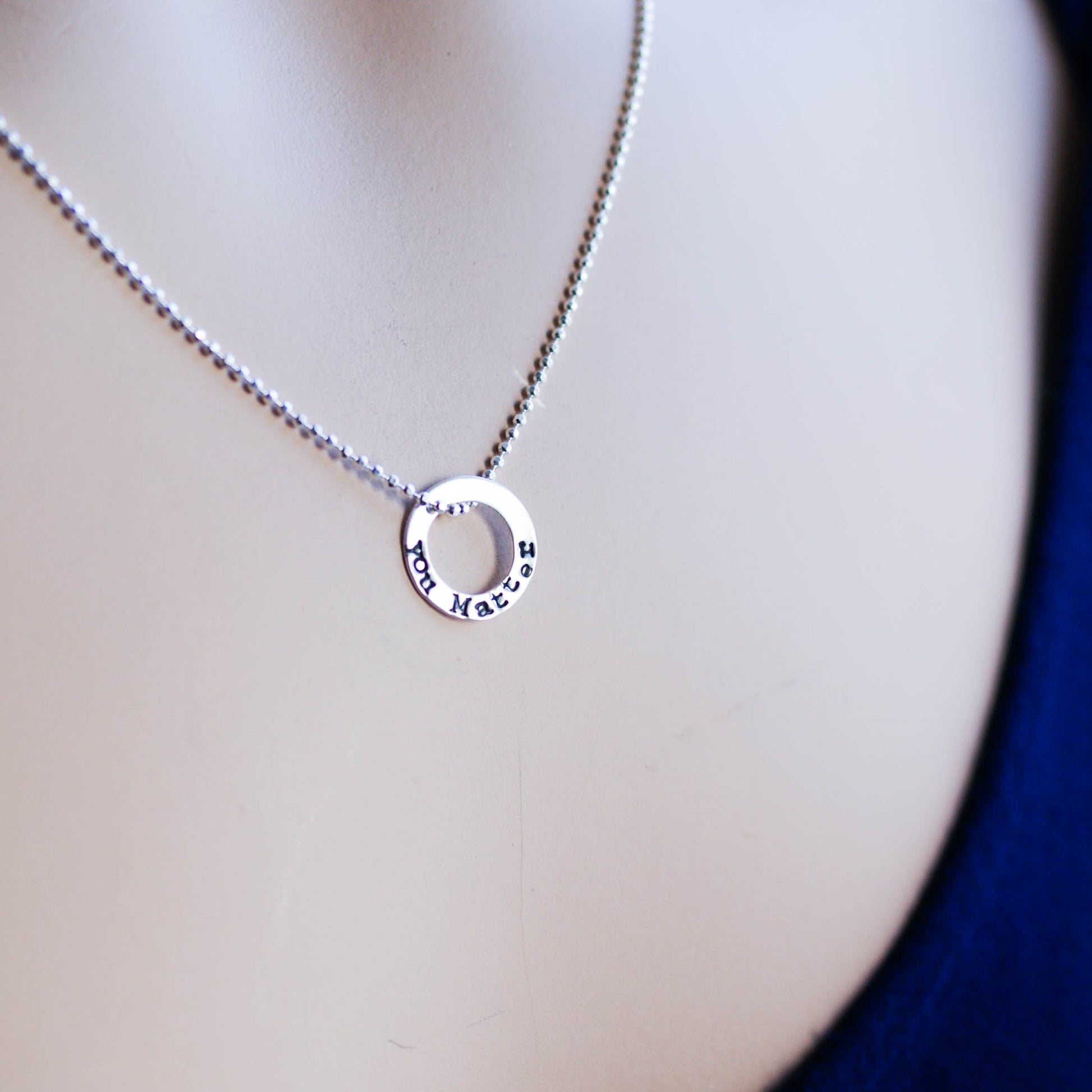 Tiny circle necklace in sterling silver stamped with You Matter on neck