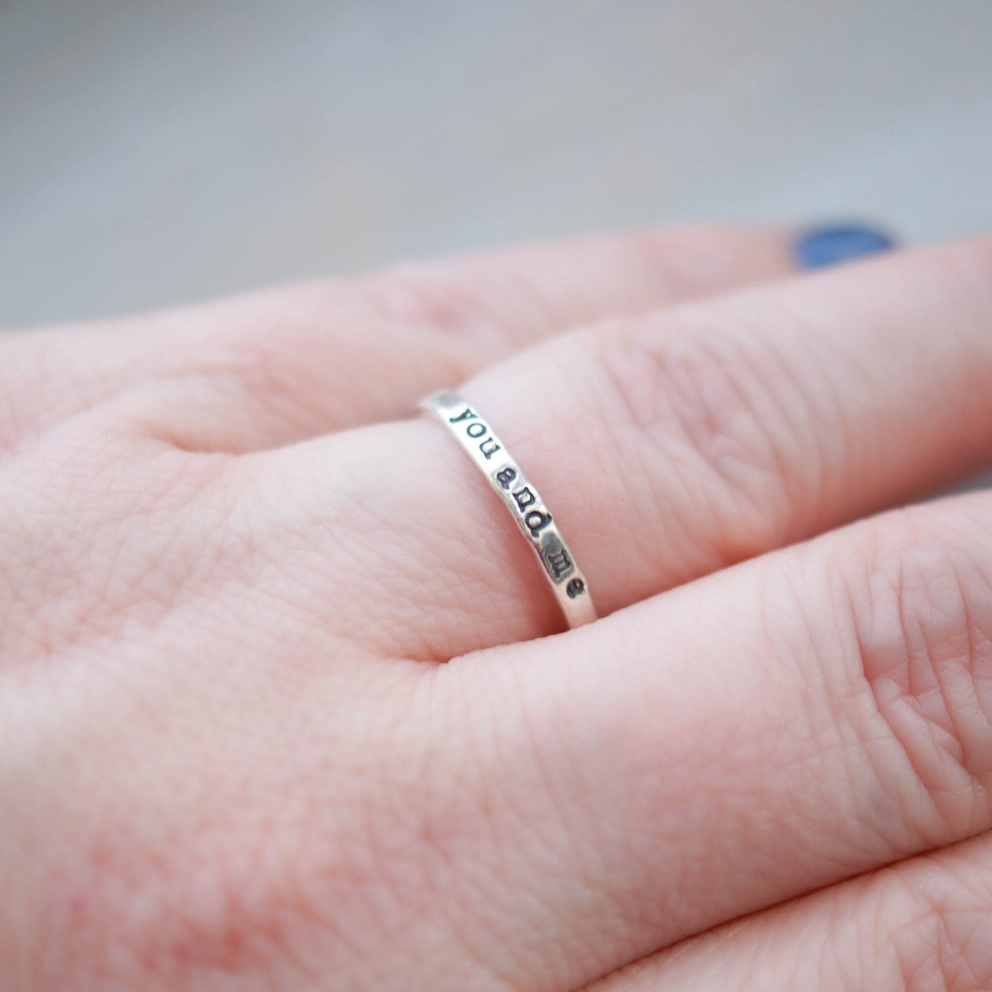 Skinny sterling silver ring stamped with you and me on hand