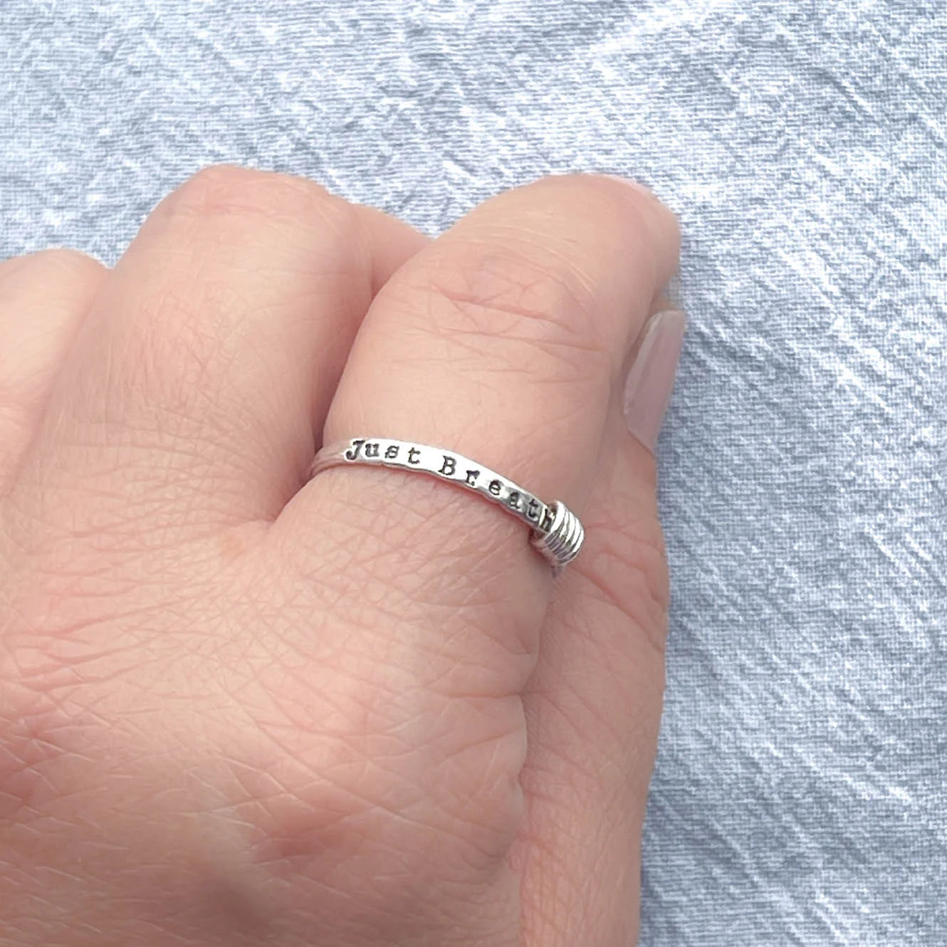 image of sterling silver ring stamped with Just Breathe on a hand