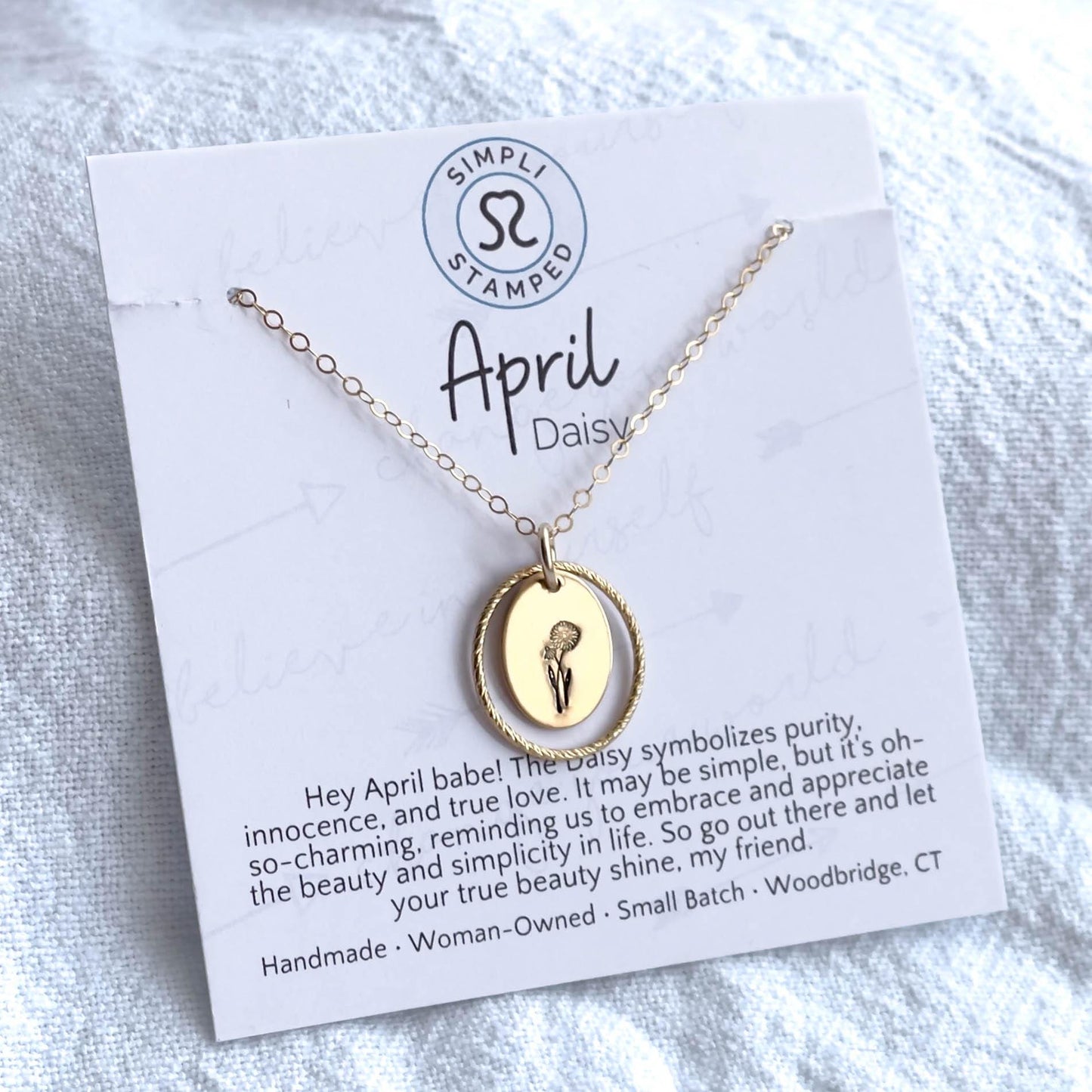 image of an oval gold birth flower necklace with a daisy stamped on it for april and a sparkle oval link surrounding it. This is on an affirmation card that says april.