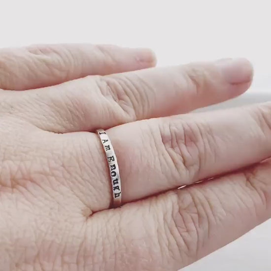 Sterling Silver stacking ring handstmaped with I Am Enough on hand and being held