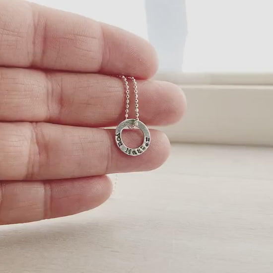 Tiny circle necklace in sterling silver stamped with You Matter on hand and on neck