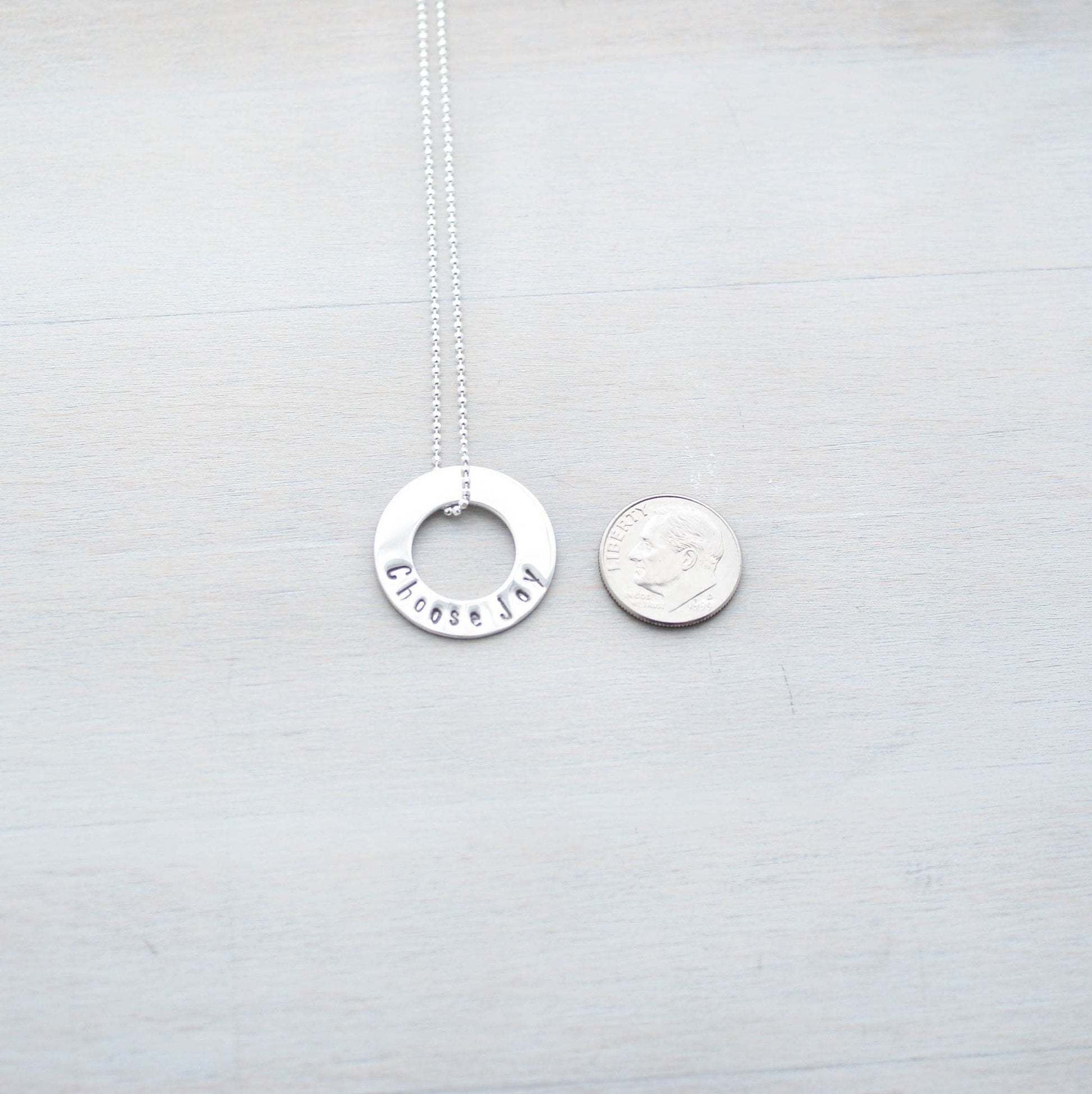 Choose Joy Circle Necklace in Sterling Silver next to dime for scale