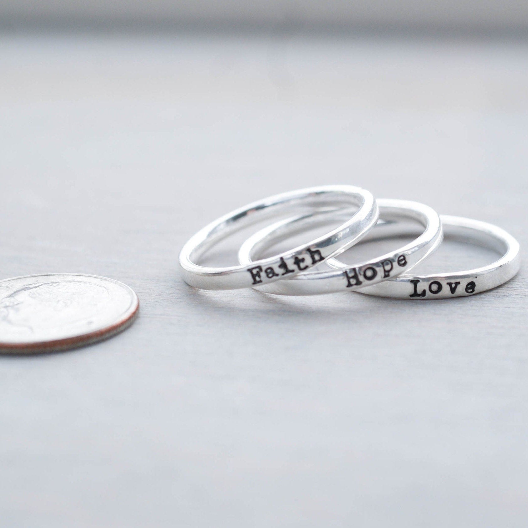 3 Sterling silver rings stamped with Faith, hope and love next to dime
