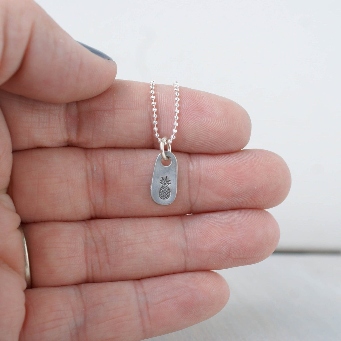 Dainty silver Pineapple necklace in artisan pewter on hand