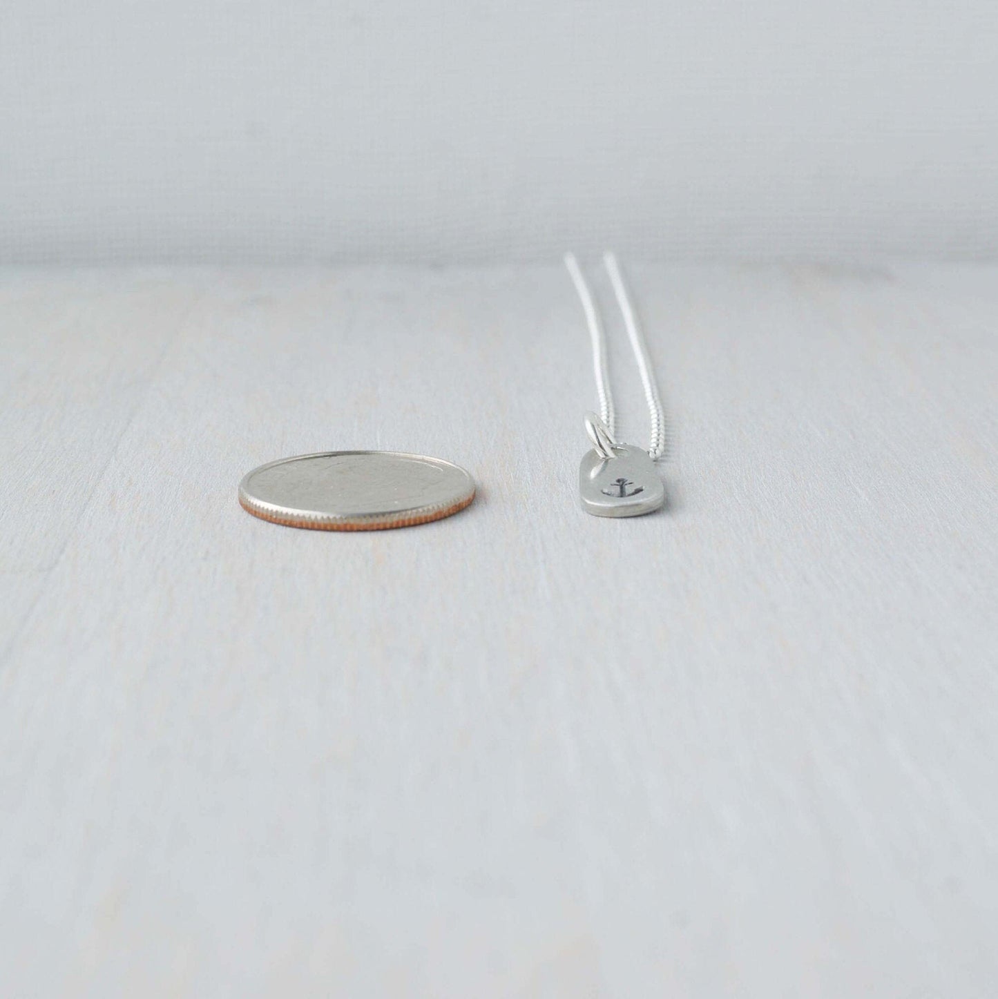 Dainty Handstamped Anchor Necklace in Pewter next to dime for scale