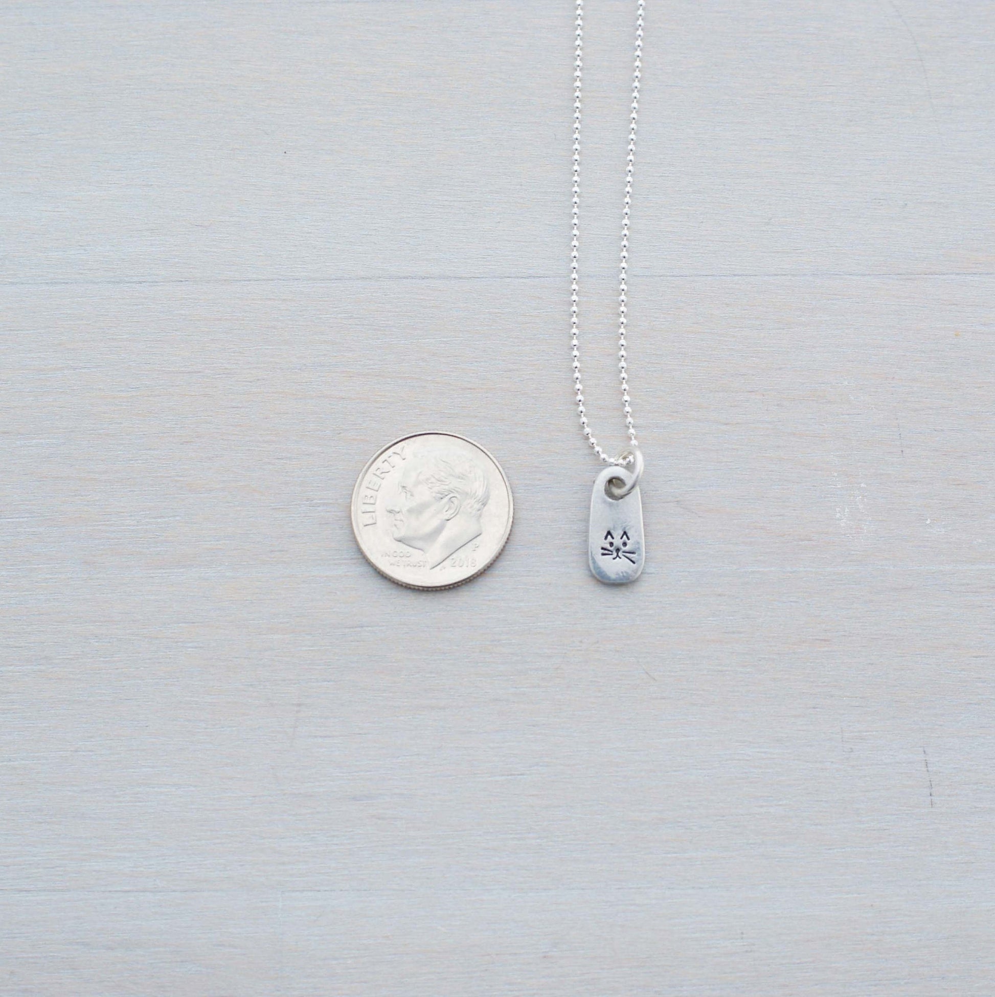 Petite Silver Necklace in Artisan Pewter with handstamped kitty face next to dim