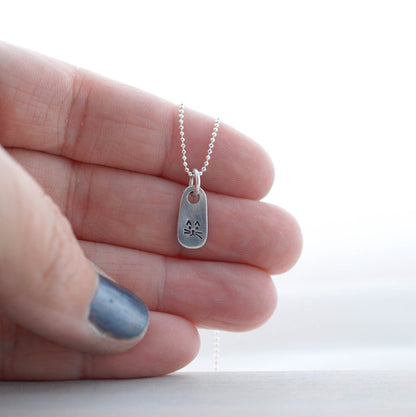 Petite Silver Necklace in Artisan Pewter with handstamped kitty face being held in hand