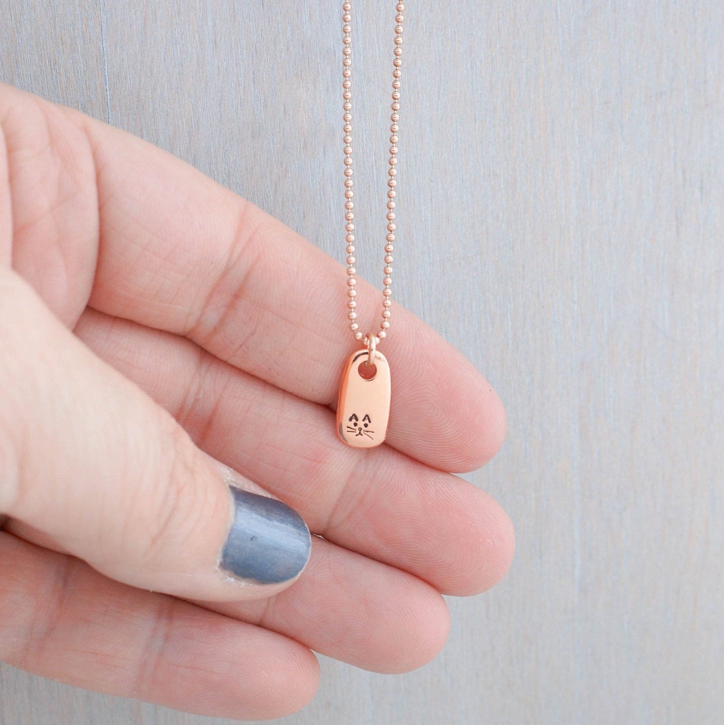 Petite Rose Gold Necklace handstamped with a kitty face in hand