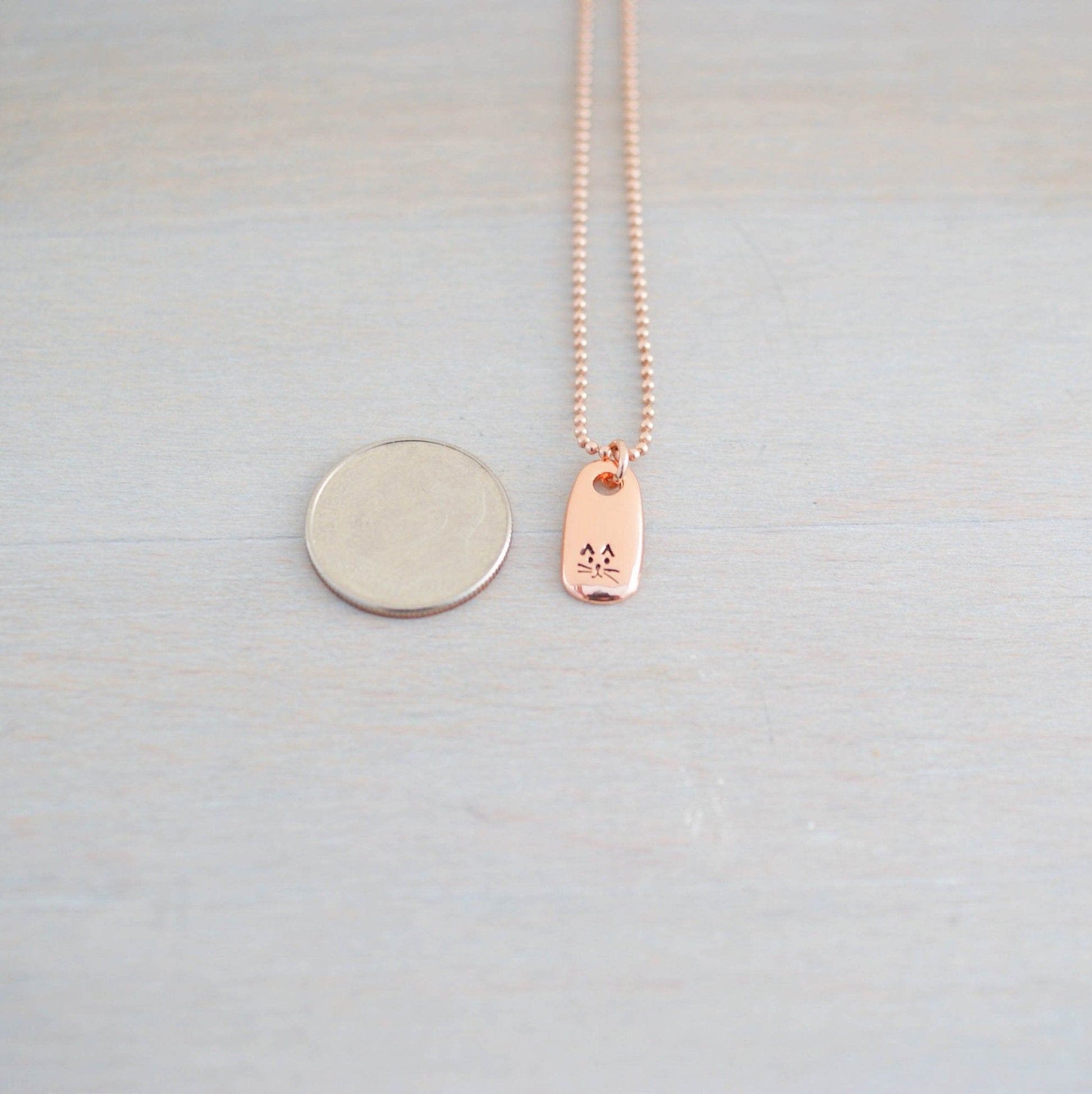 Petite Rose Gold Necklace handstamped with a kitty face next to a dime