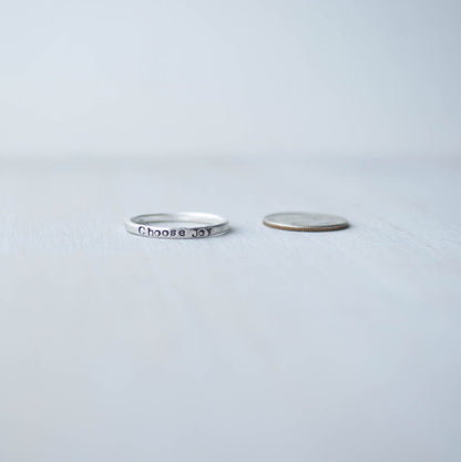 Stacking ring in Sterling silver handstamped with Choose Joy next to dime