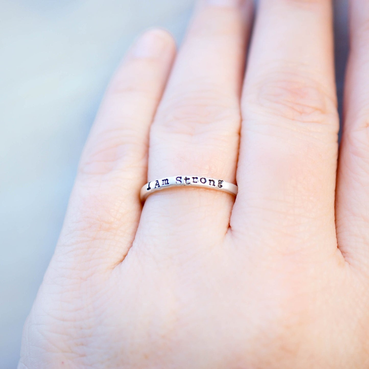 Sterling Silver stacking ring handstmaped with I Am Strong on hand