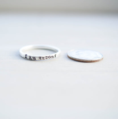 Sterling Silver ring stamped with I Am Strong next to dime