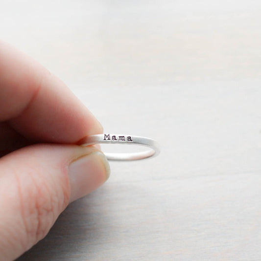 Sterling silver ring handstamped with Mama held between fingers