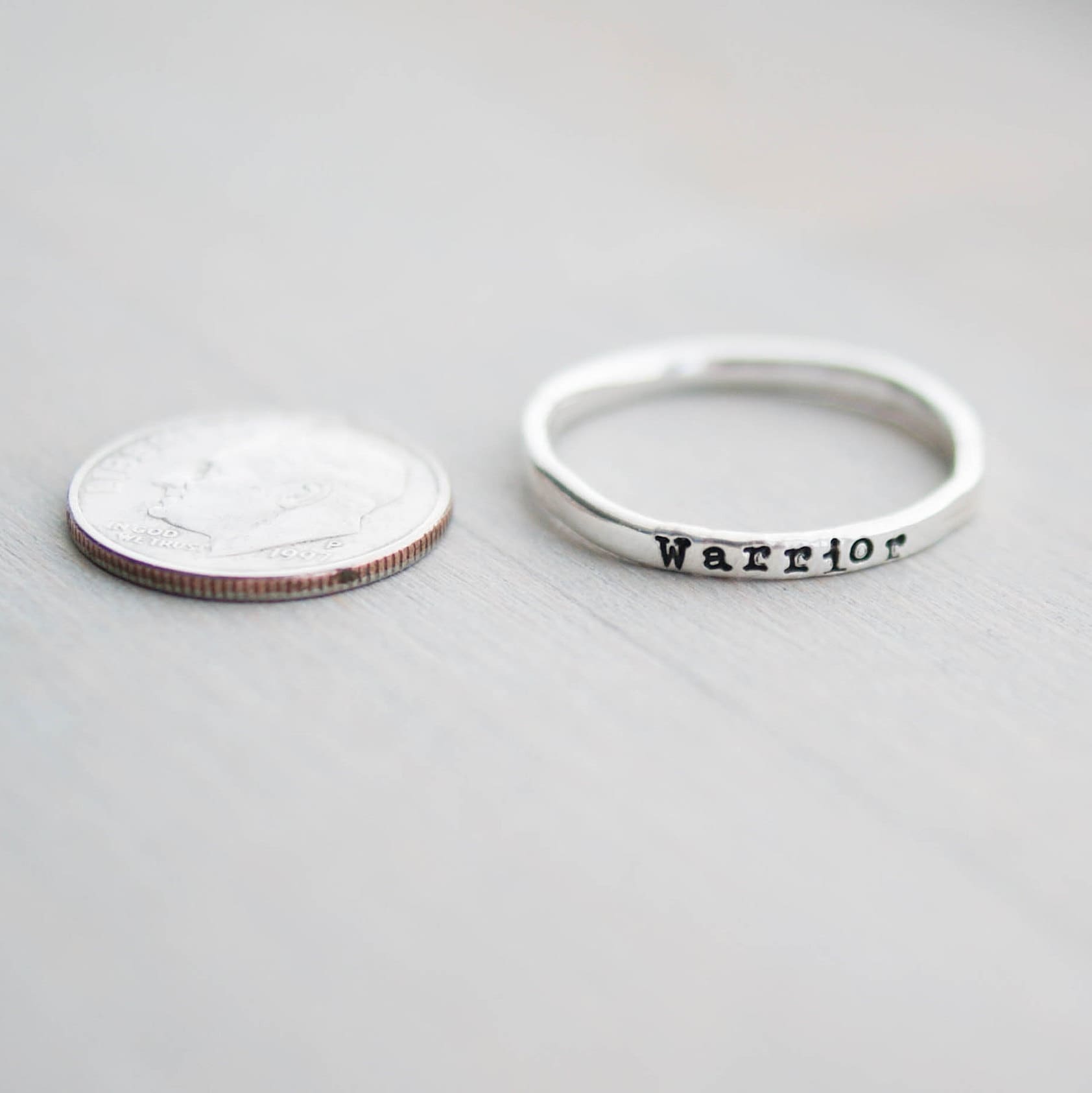 Sterling silver ring stamped with Warrior next to dime