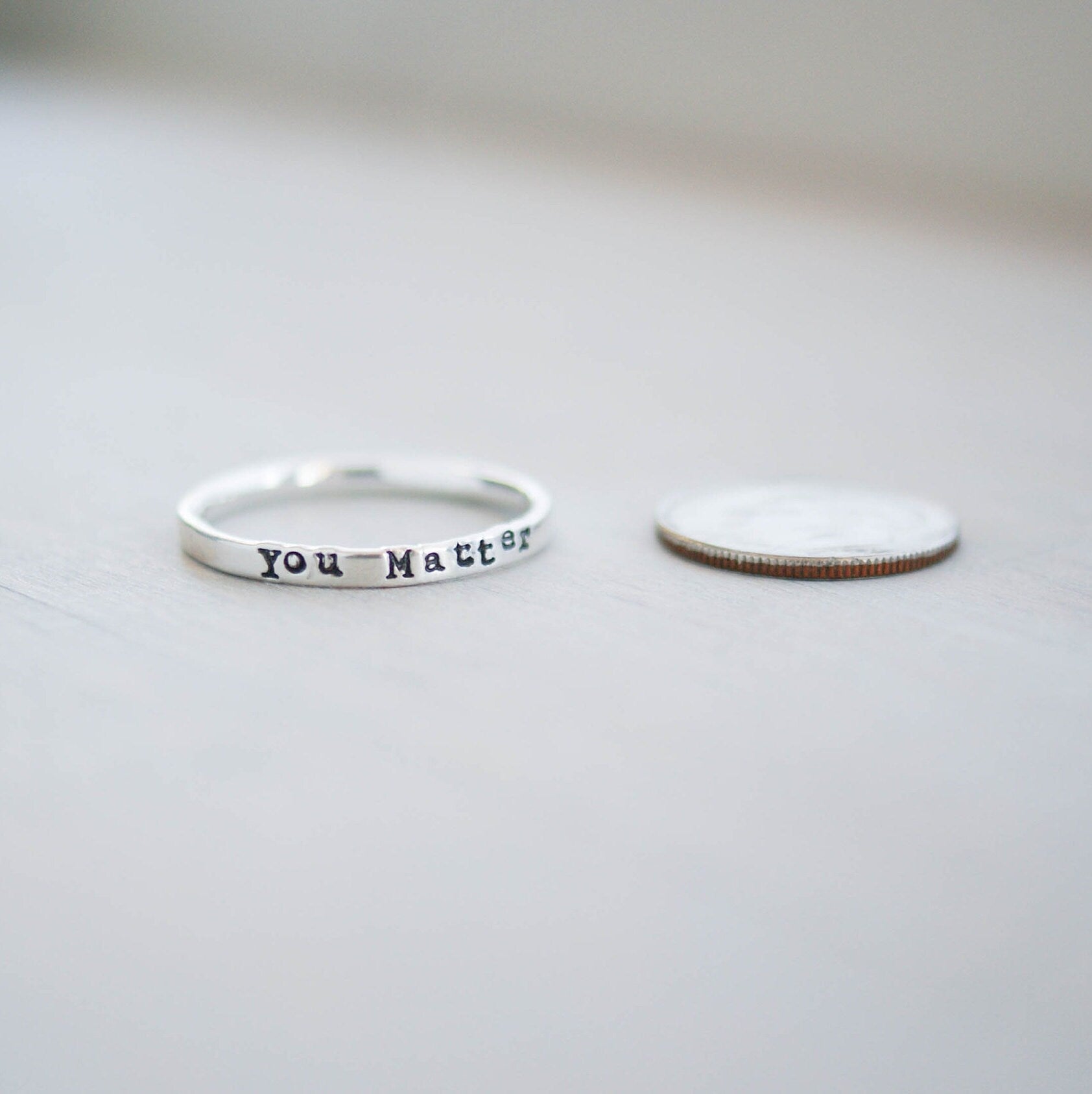 Sterling silver ring stamped with you matter next to dime