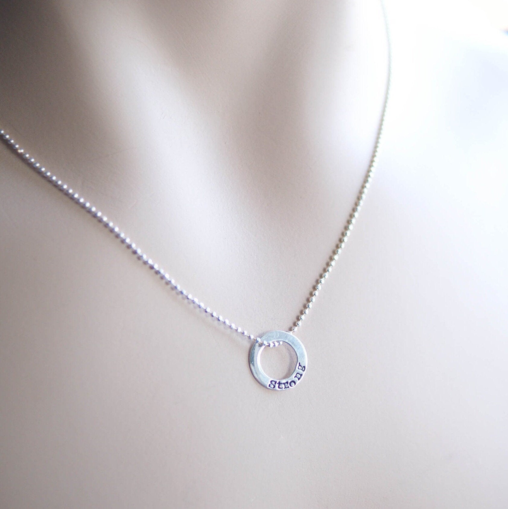 Sterling silver tiny circle stamped with Strong necklace on neck