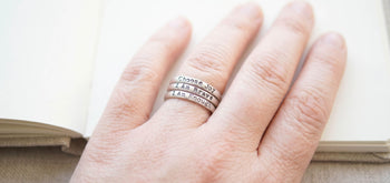 hand resting on a book wearing 3 stacking rings saying Choose Joy , I Am Brave, I Am Enough