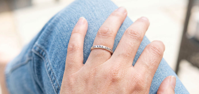 image of hand wearing i am the storm strength ring resting on knee wearing jeans