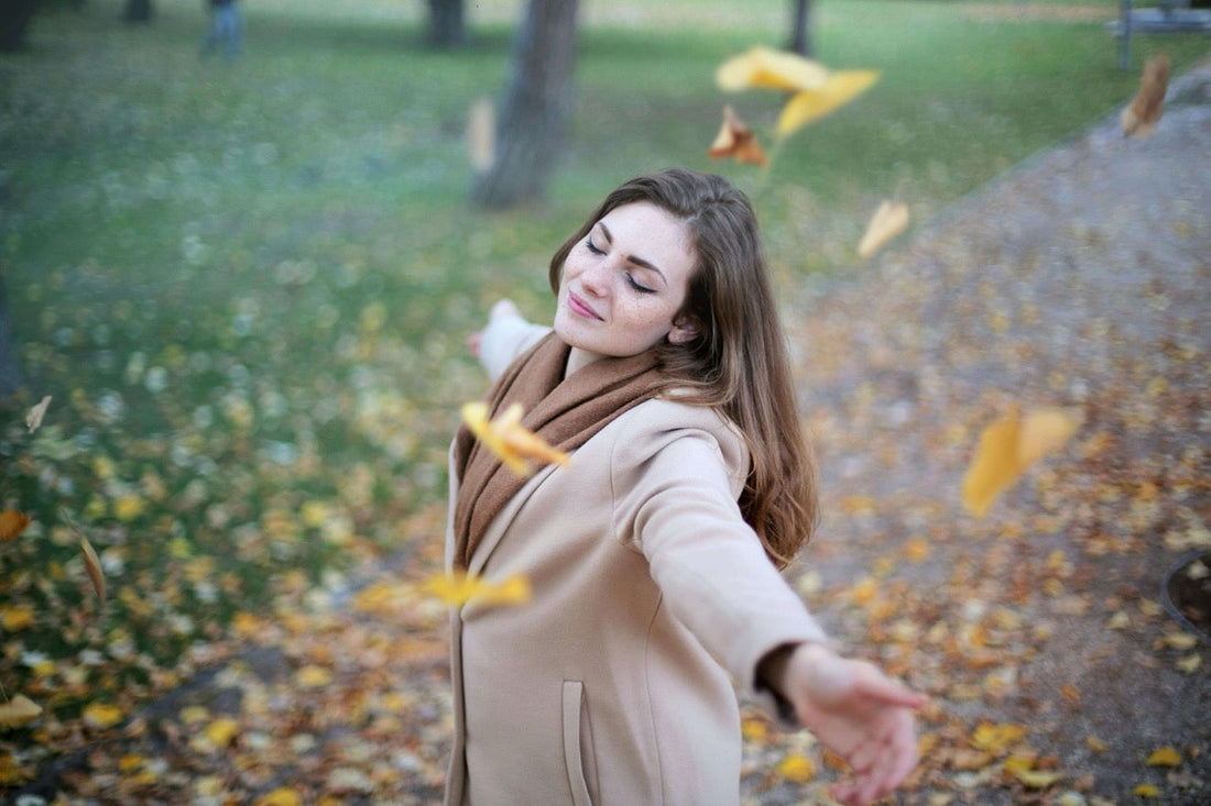 image of woman with arms raised in freedom with  autumn leaves fallin gdown on them