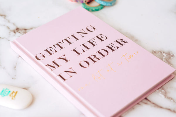 image of a pink book for setting intentions for the new year titled  "getting my life in order" on a marble desk