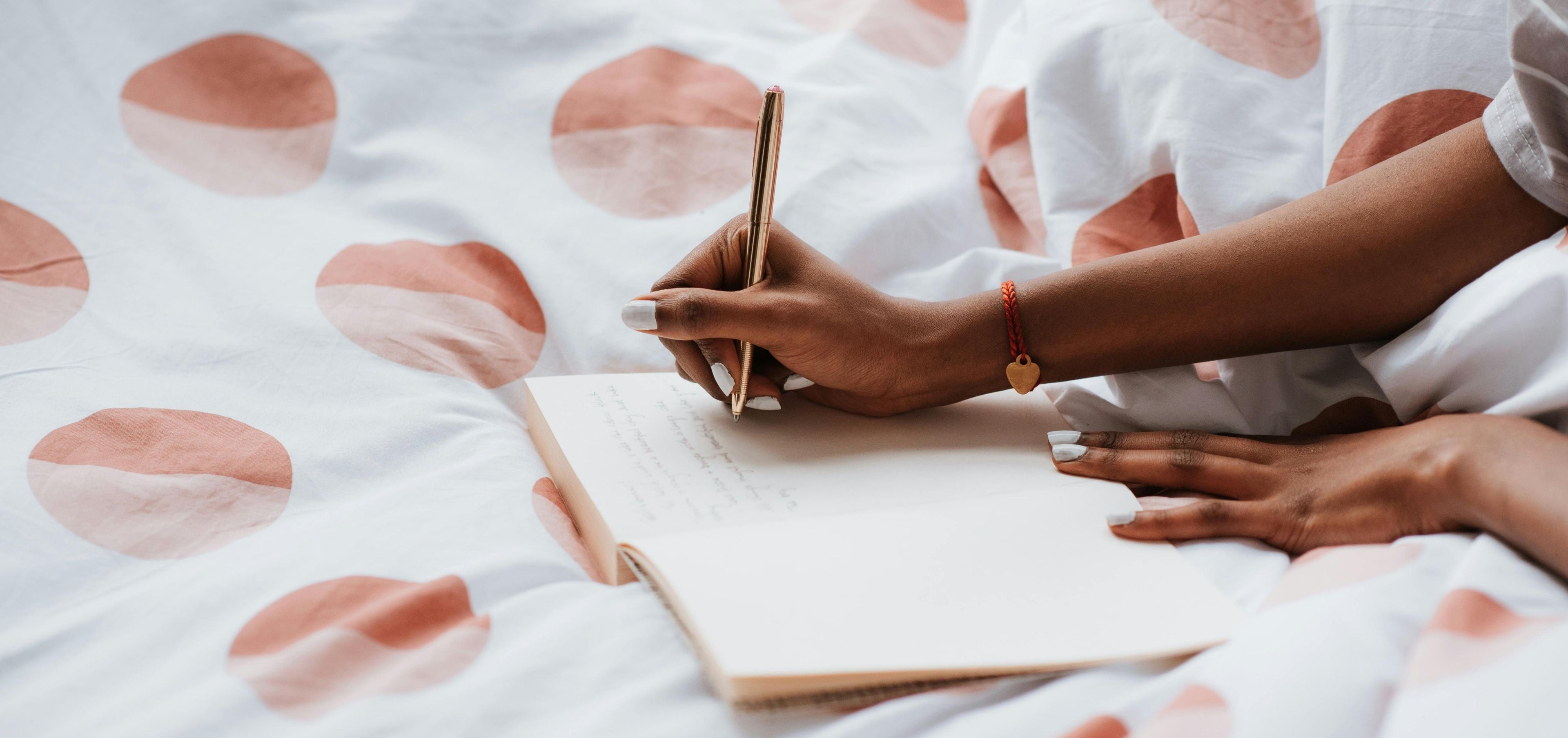 image of woman journaling on white with red spots bed spread