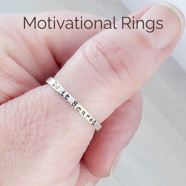image of hand stamped ring that says Just Breathe with spinner rings on hand sitting on grey background