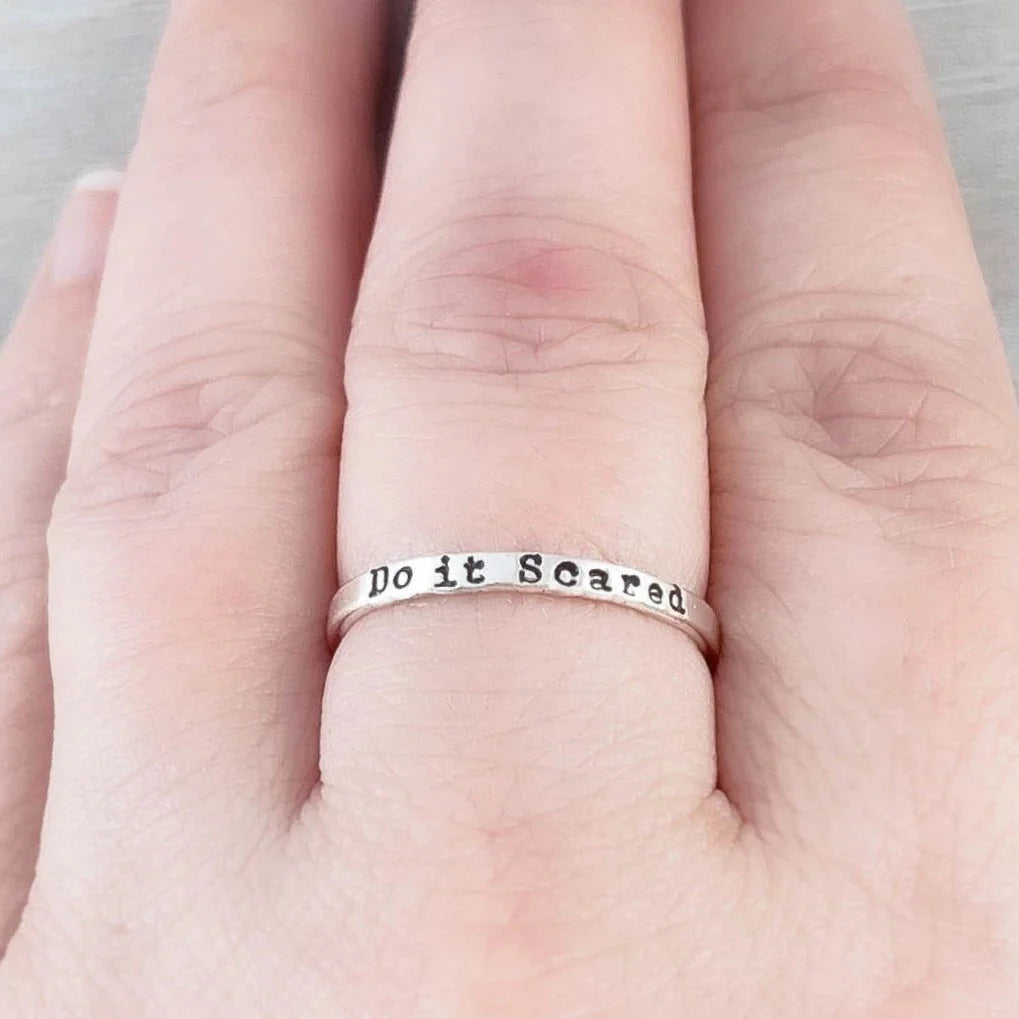 image of hand stamped ring that says Just Breathe with spinner rings on hand sitting on grey background