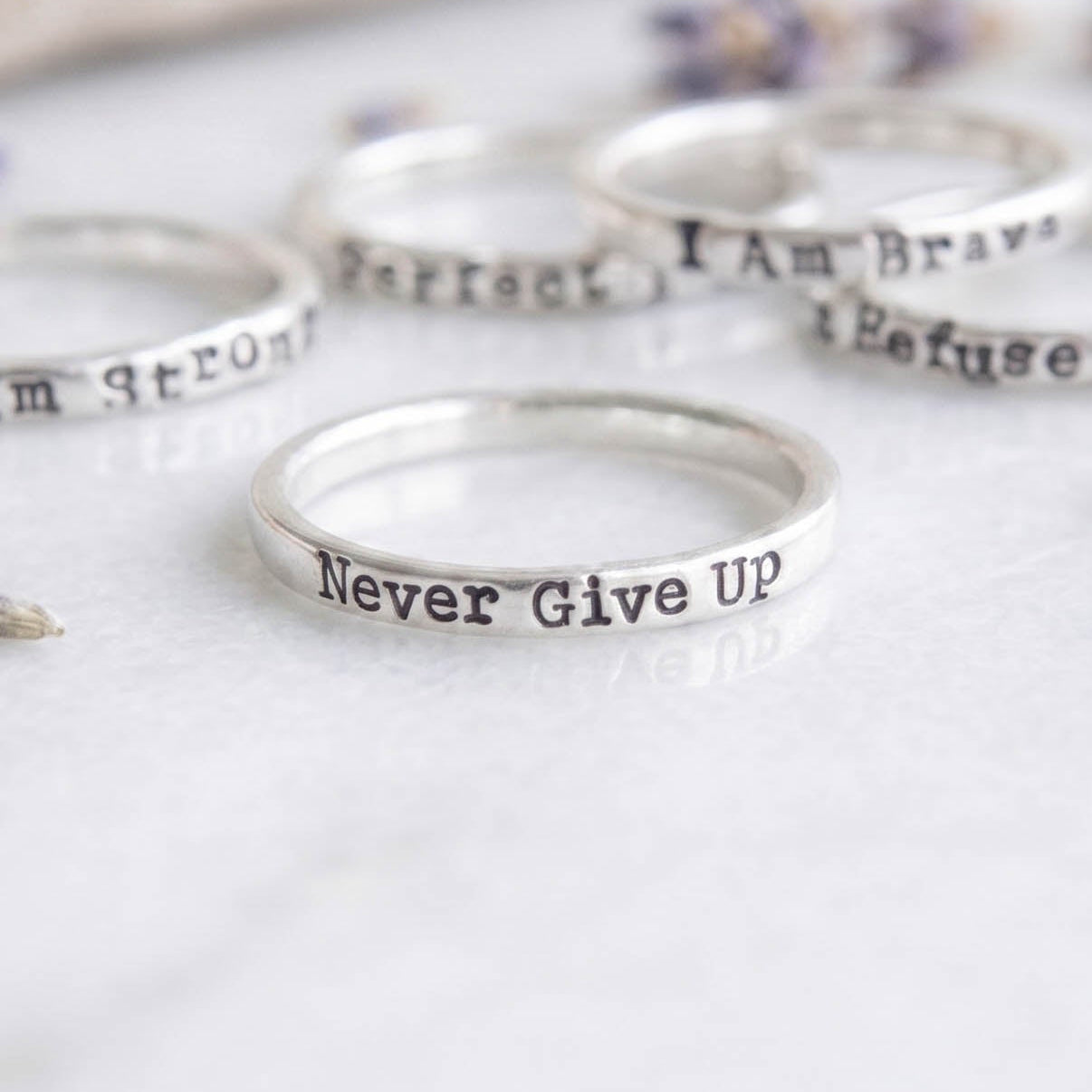 Sterling silver choose your words motivational ring on a white background with other rings behind