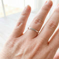 Hand wearing a silver ring with 'Jessie' stamped on it against a blurred background.
