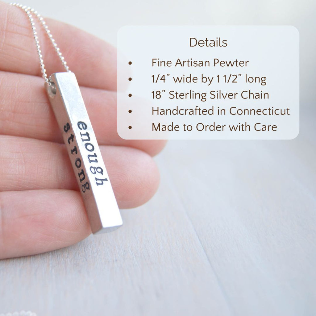 image of silver bar necklace stamped with strong, brave, enough, one on each side being held in a hand. product details are overlayed. Fine Artisan Pewter, 1/4” wide by 1/2” long, 18” Sterling Silver Chain.