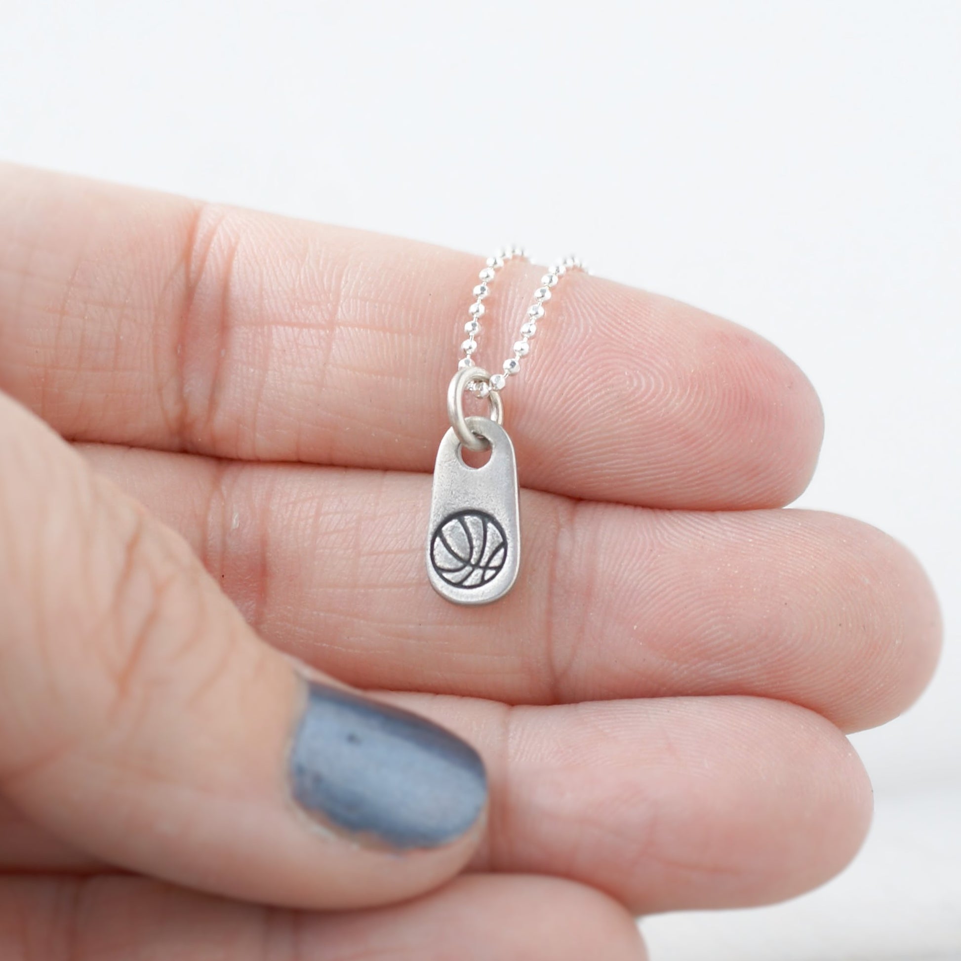 Silver mom jewelry basketball necklace in artisan pewter in hand