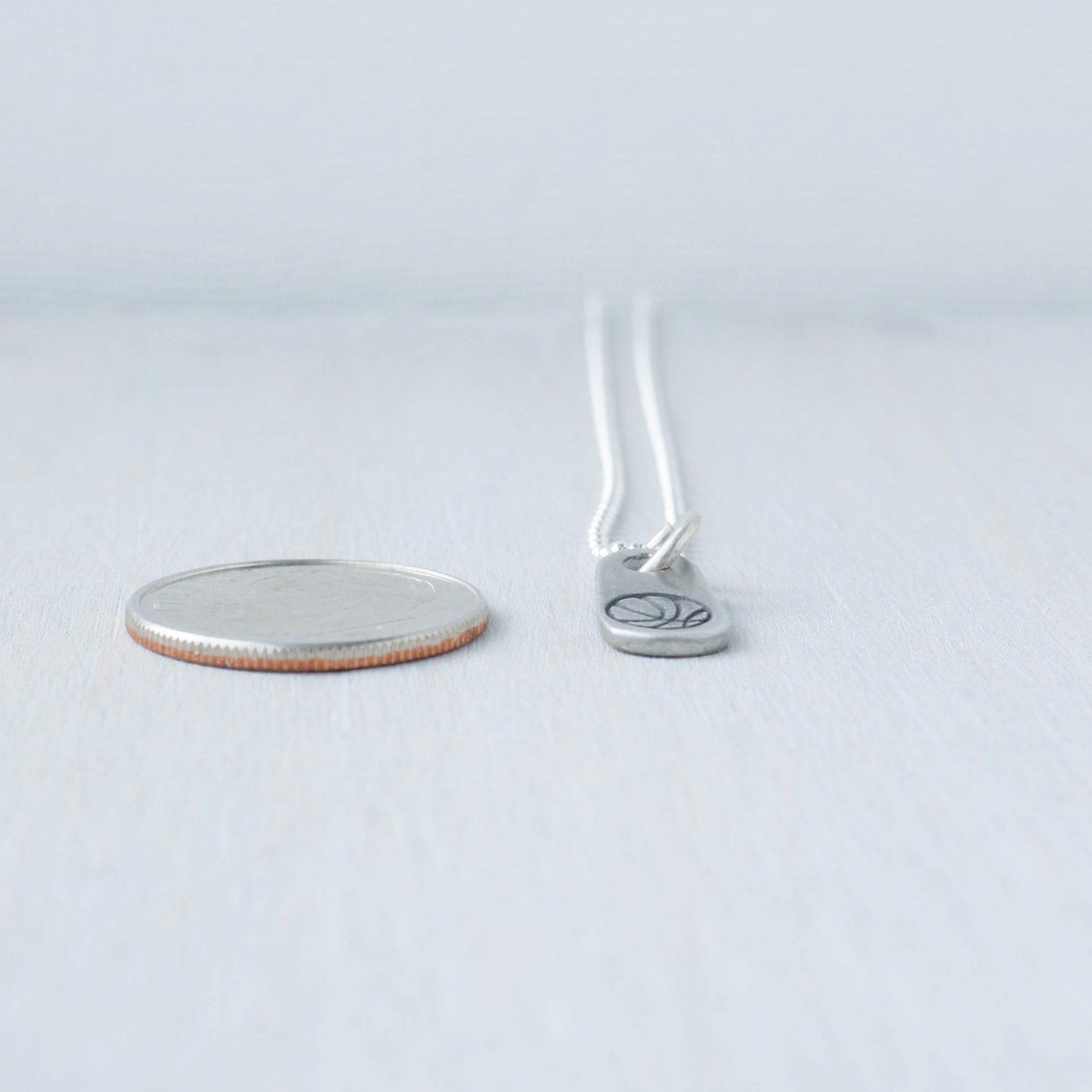 Silver basketball necklace in artisan pewter next to dime