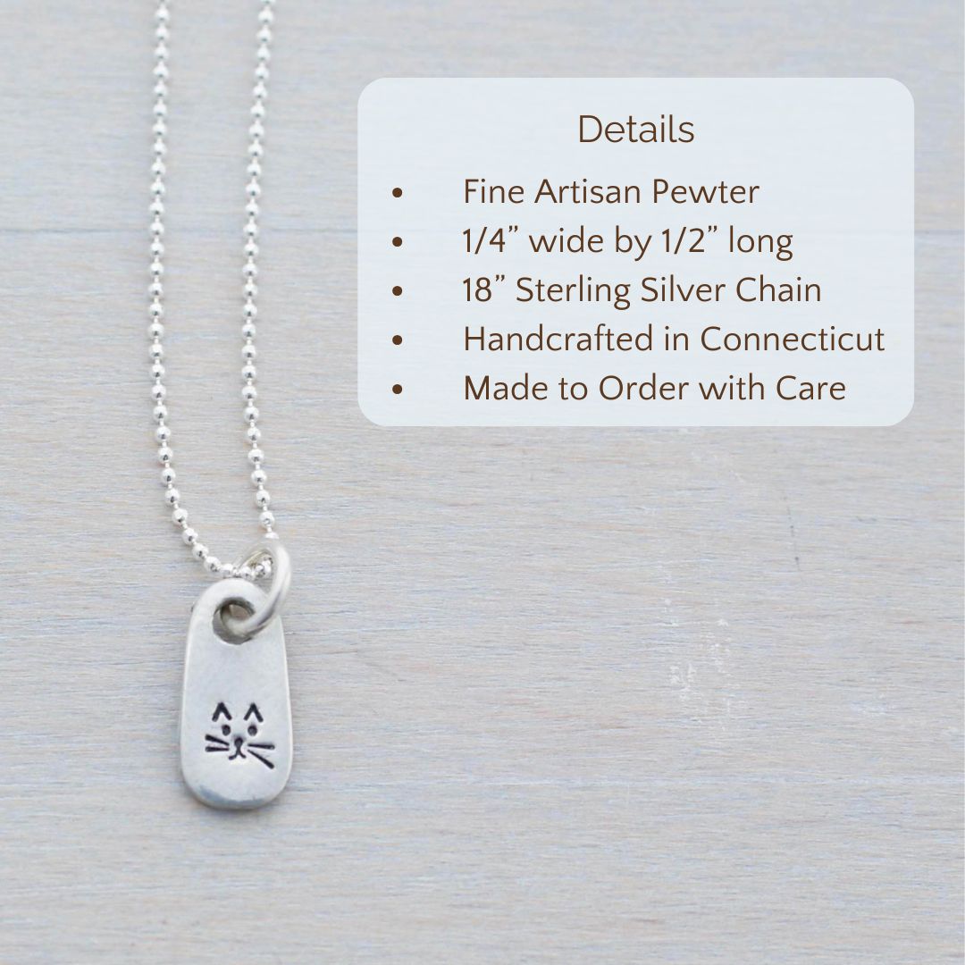 image of silver necklace with quirky cat face stamped on it. product details are overlayed. Fine Artisan Pewter, 1/4” wide by 1/2” long, 18” Sterling Silver Chain