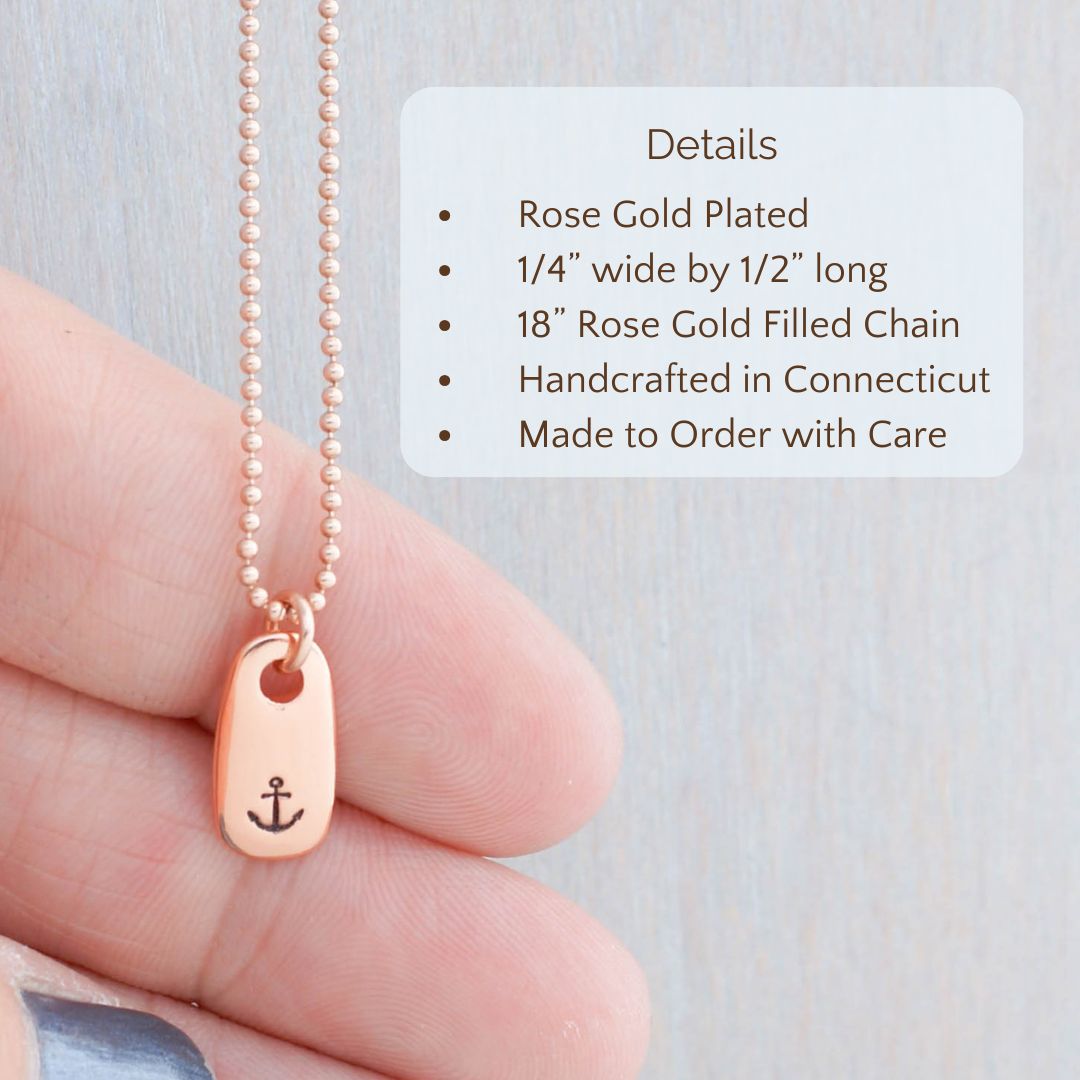 image of rose gold necklace with anchor stamped on it held in a hand. product details are overlayed, Rose Gold Plated, 1/4” wide by 1/2” long, 18” Rose Gold Filled Chain
