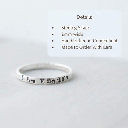 Image of I Am Enough ring stamped on a hand with the product details overlayed. Sterling silver, 2mm wide, handcrafted in connecticut, made to order with care.