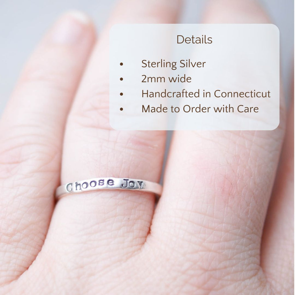 Image of Choose Joy ring stamped on a hand with the product details overlayed. Sterling silver, 2mm wide, handcrafted in connecticut, made to order with care.