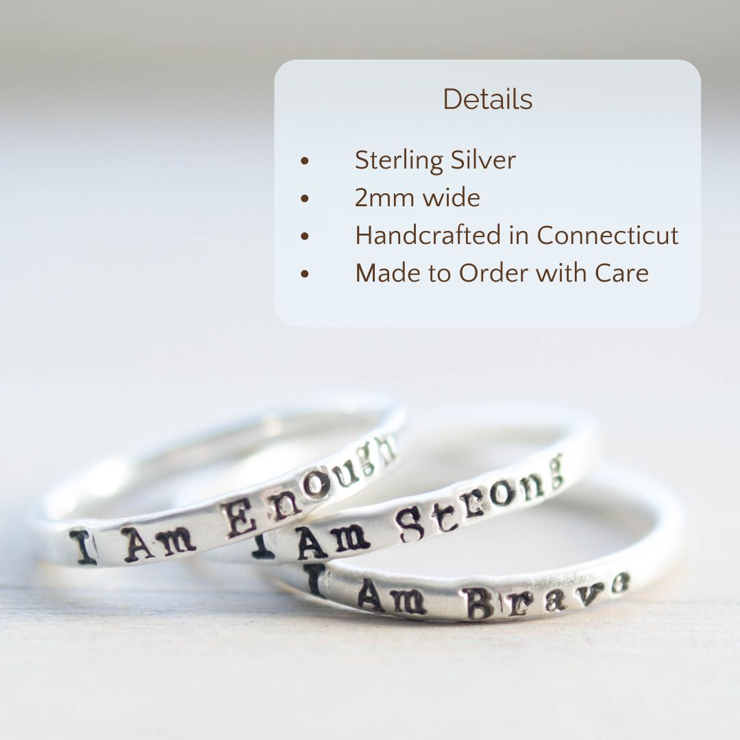 Image of 3 rings, each stamped with I Am Strong, I Am Brave, I Am Enough on a hand with the product details overlayed. Sterling silver, 2mm wide, handcrafted in connecticut, made to order with care.