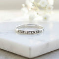 Silver ring with 'Refuse to Sink' stamped on a marble surface