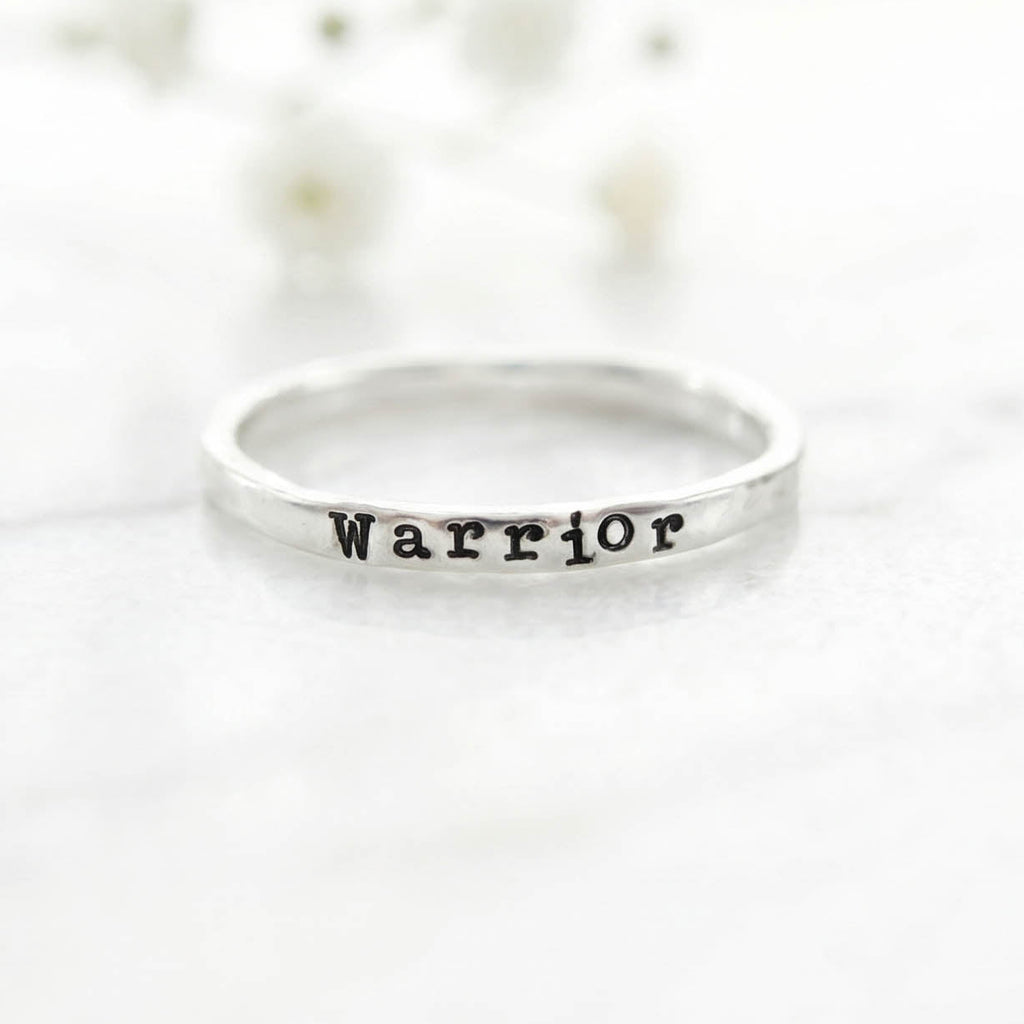 Silver ring with 'Warrior' stamped on a white background