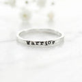 Silver ring with 'Warrior' stamped on a white background