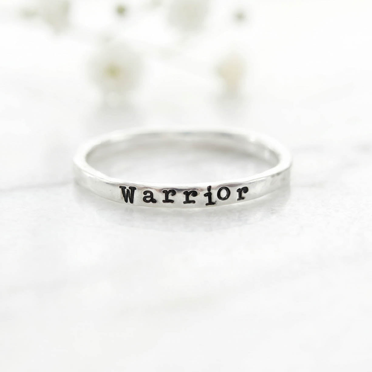 Silver ring with 'Warrior' stamped on a white background
