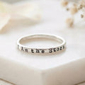 Silver ring with 'I Am the Storm' engraving on a white surface