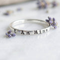 Silver ring with 'I Am Mine' stamped on a white background with lavender flowers.