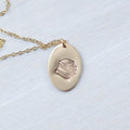 Gold oval necklace stamped with a stack of books