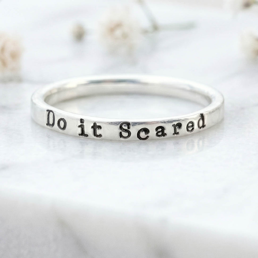Silver ring with 'Do it Scared' engraving on a light background